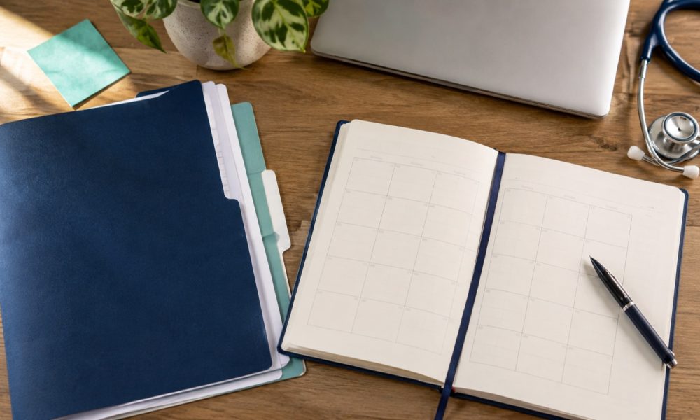 Undated planner, application folders, and a stethoscope on a desk for PA school application planning